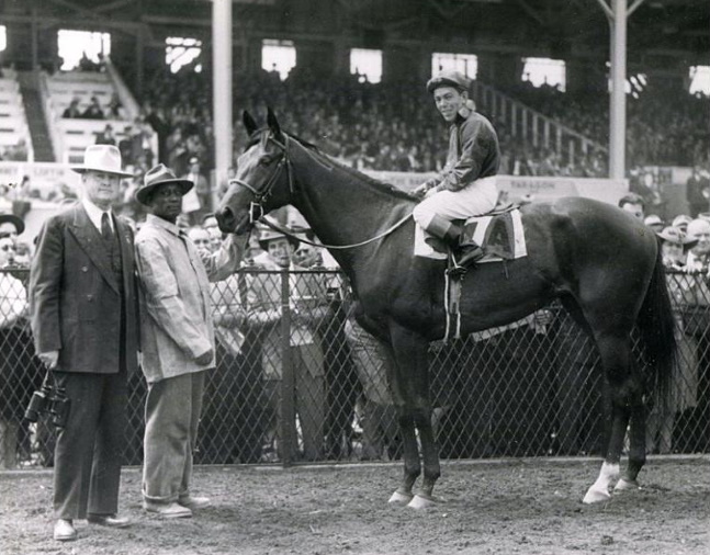 Twilight Tear (Conn McCreary up) in the winner's circle with trainer Ben Jones after winning the 1944 Rennert Handicap at Pimlico (The BloodHorse/Museum Collection)