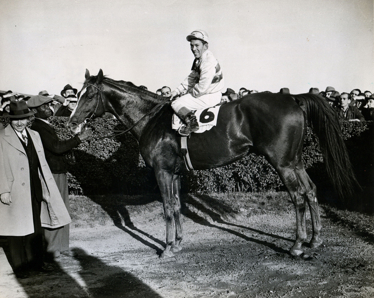 Conn McCreary and Stymie in the winner's circle with trainer Hirsch Jacobs after winning the 1947 Gallant Fox Handicap at Jamaica (Museum Collection)
